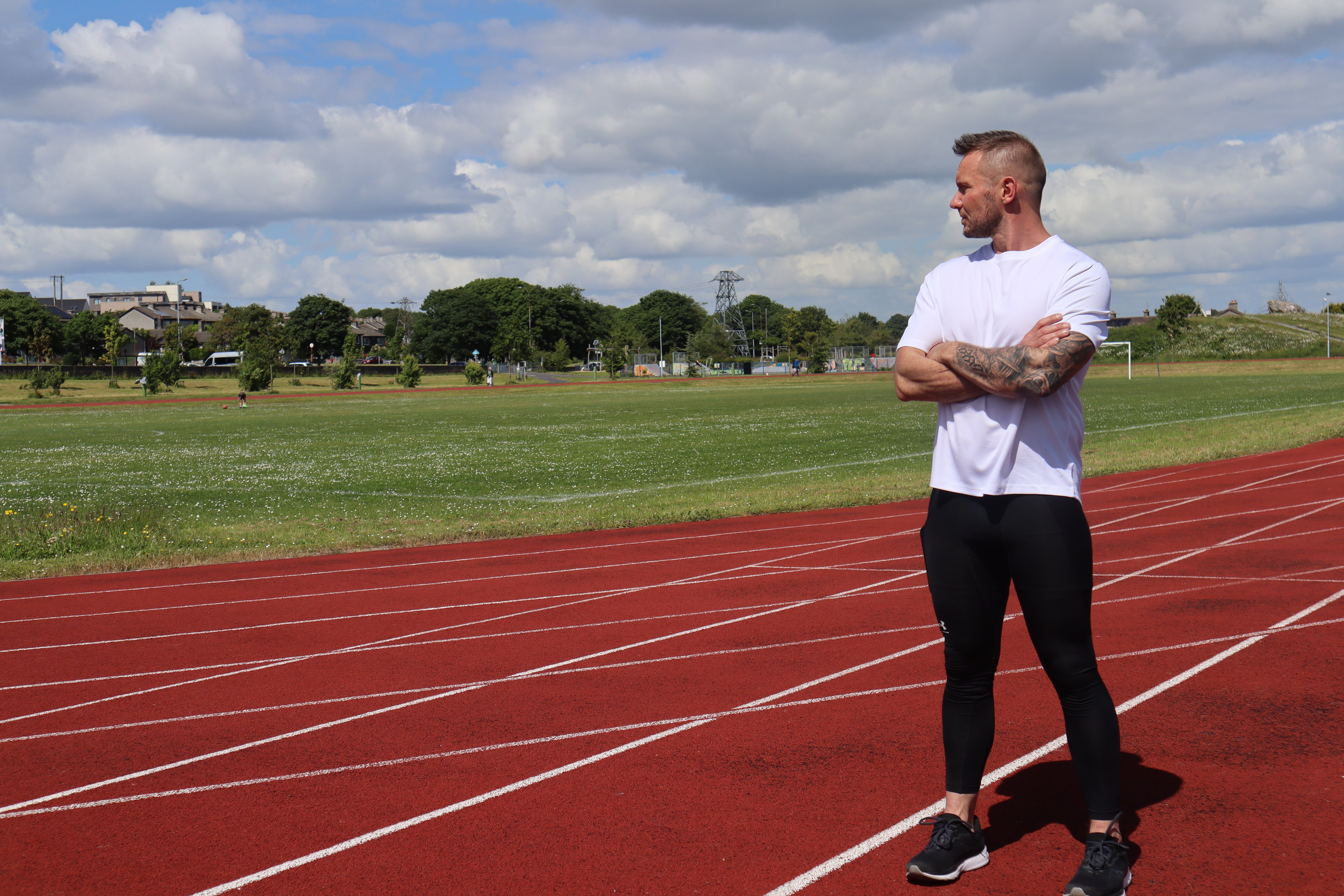 Jason Cafferkey, running coach and speed development expert in Galway, in sprint start position on a red running track, preparing for explosive speed training for athletes, GAA Athletes, busy moms, busy dads, and fitness clients.