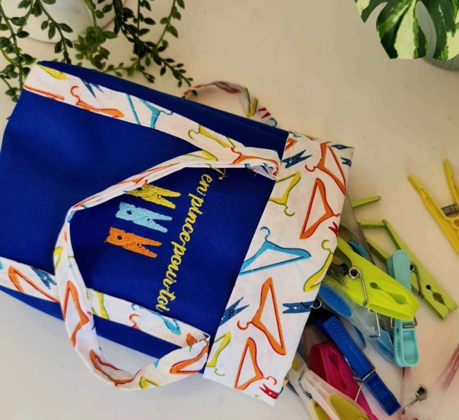 Mini cabas MALA posé sur une table en bois clair, cousu en tissu fleuri avec rabat contrastant