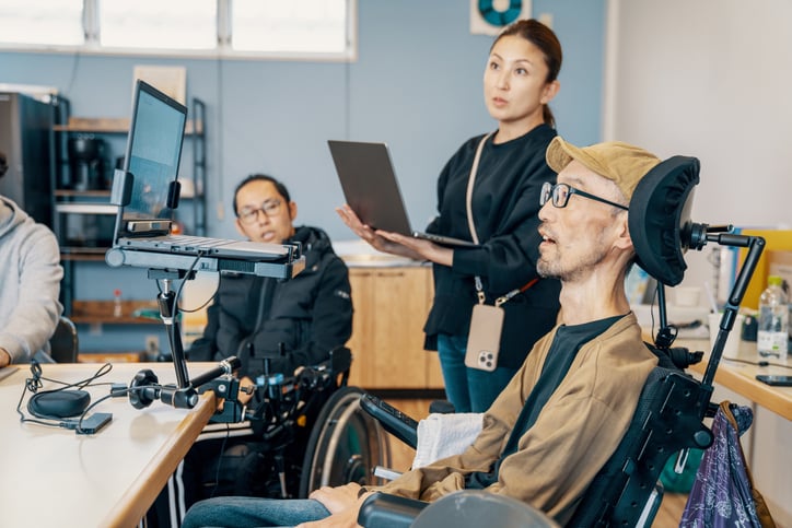 a team including a disabled manager discuss designs on a computer screen