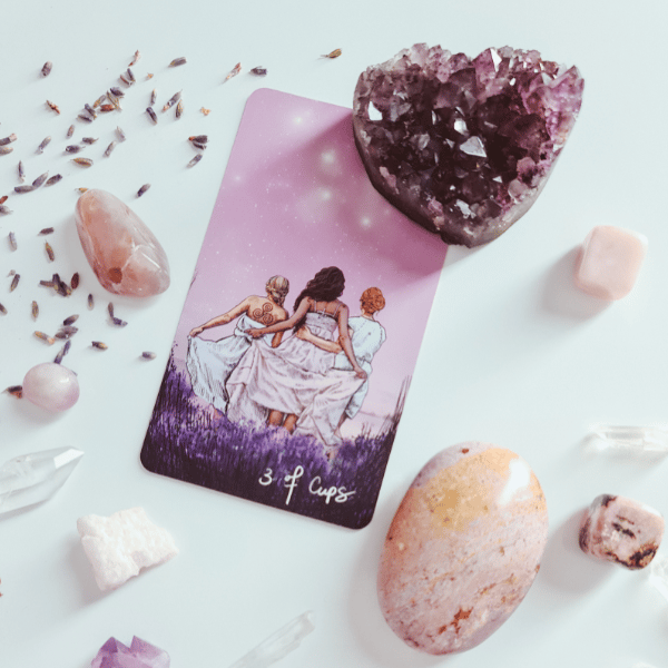 Three of Cups tarot card surrounded by rose quartz crystals and amethyst geode — image for Intuitive Tarot Readings page on iamisabelbar.com
