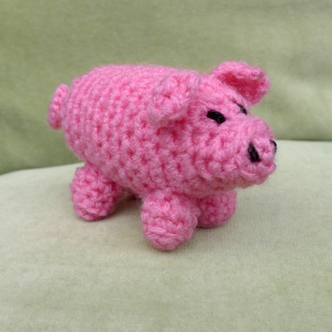 A pink crochet pig made in acrylic yarn..