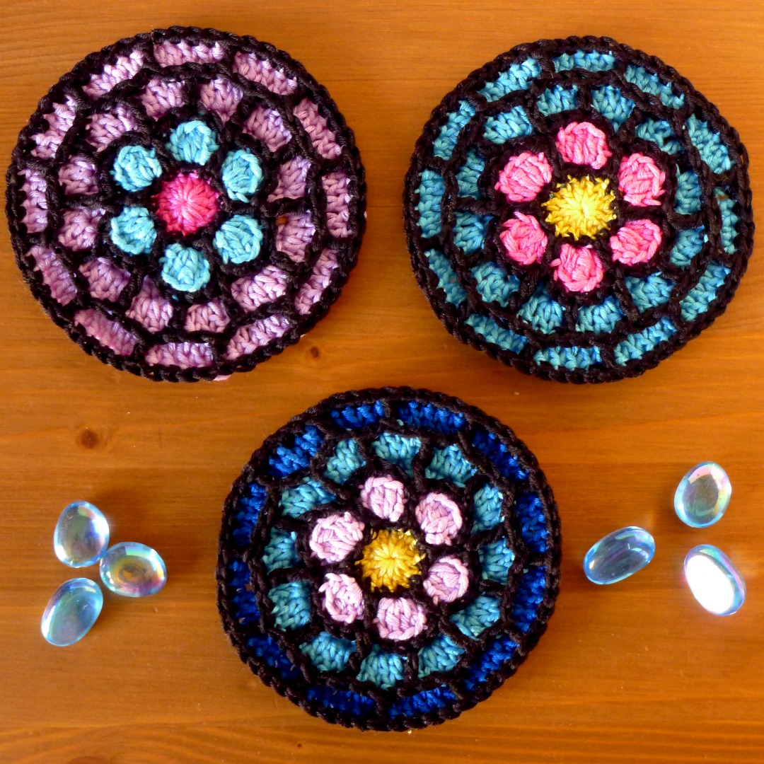 Three Rose Window Coasters in DK cotton yarn using different colours.