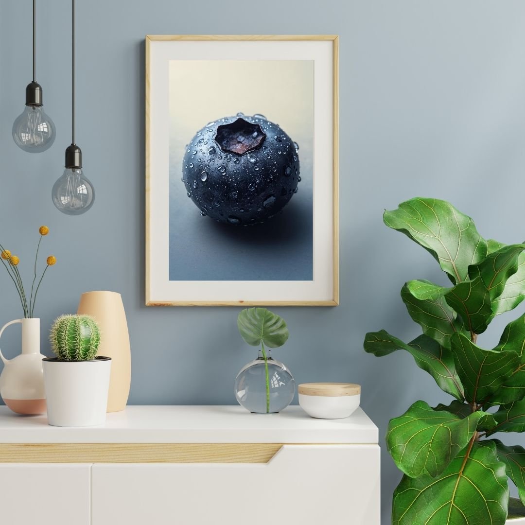 A close-up photograph of a single fresh blueberry covered in small water droplets. The berry has a smooth, dark blue surface with a matte sheen and a star-shaped calyx at the top. The soft lighting and neutral background highlight the texture and moisture