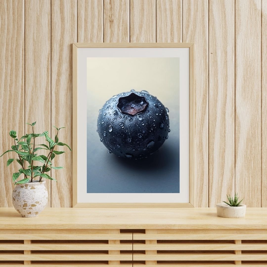 A close-up photograph of a single fresh blueberry covered in small water droplets. The berry has a smooth, dark blue surface with a matte sheen and a star-shaped calyx at the top. The soft lighting and neutral background highlight the texture and moisture