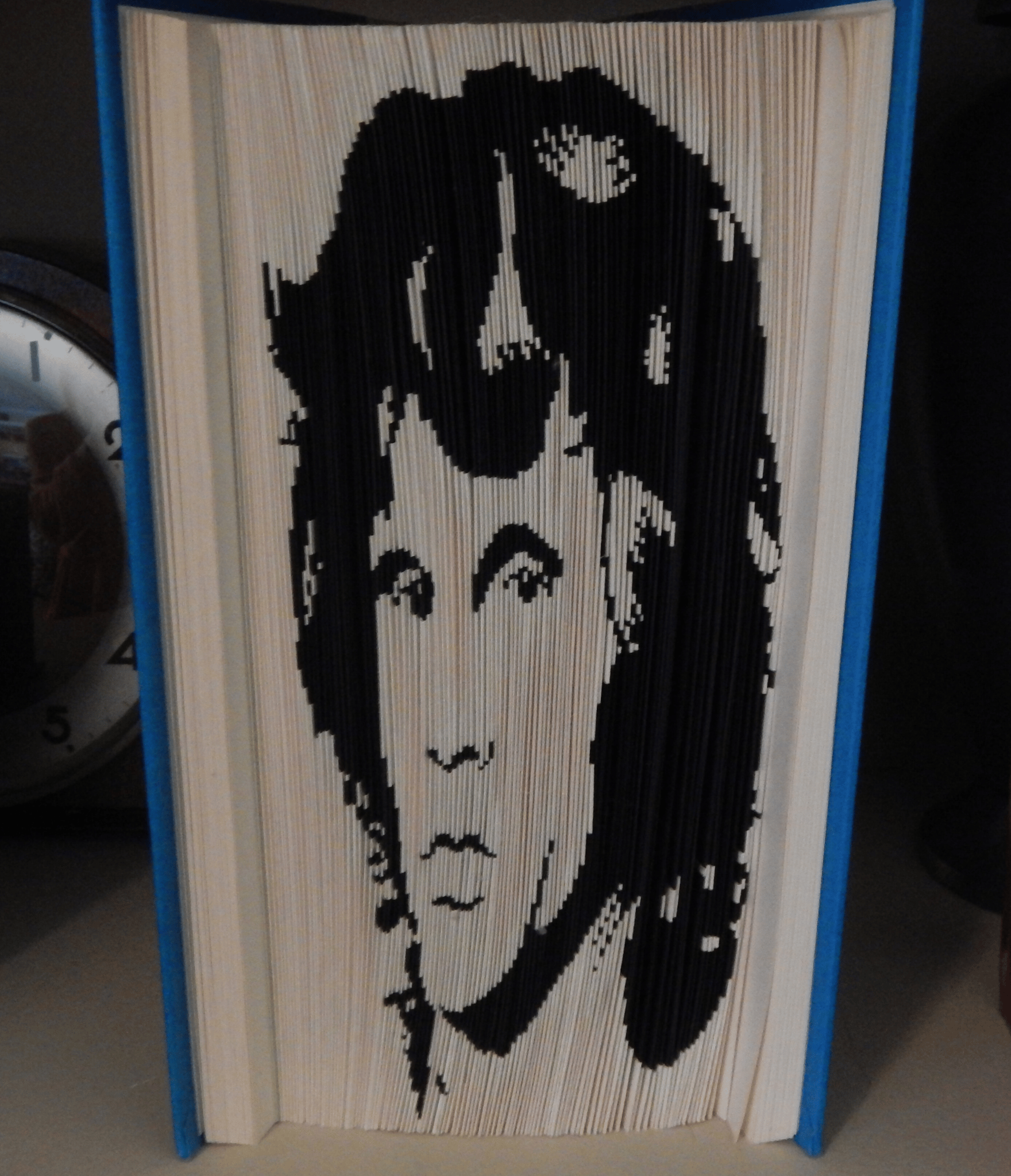A striking portrait created using a 180 cut & fold pattern with cardstock detailing for bold contrast and depth. This upcycled book art piece honors the iconic Jim Morrison — a unique blend of paper craft and music-inspired design.
