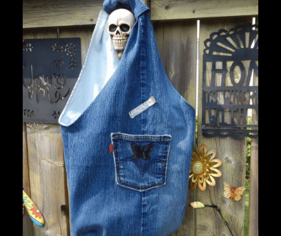 Upcycled denim shoulder bag with a slouchy hobo-style shape, handmade from recycled jeans and repurposed textiles. This sustainable boho handbag features butterfly applique details, pockets, some nostalgic labels, soft drape construction, and unique handmade craftsmanship for an effortlessly boho casual look.