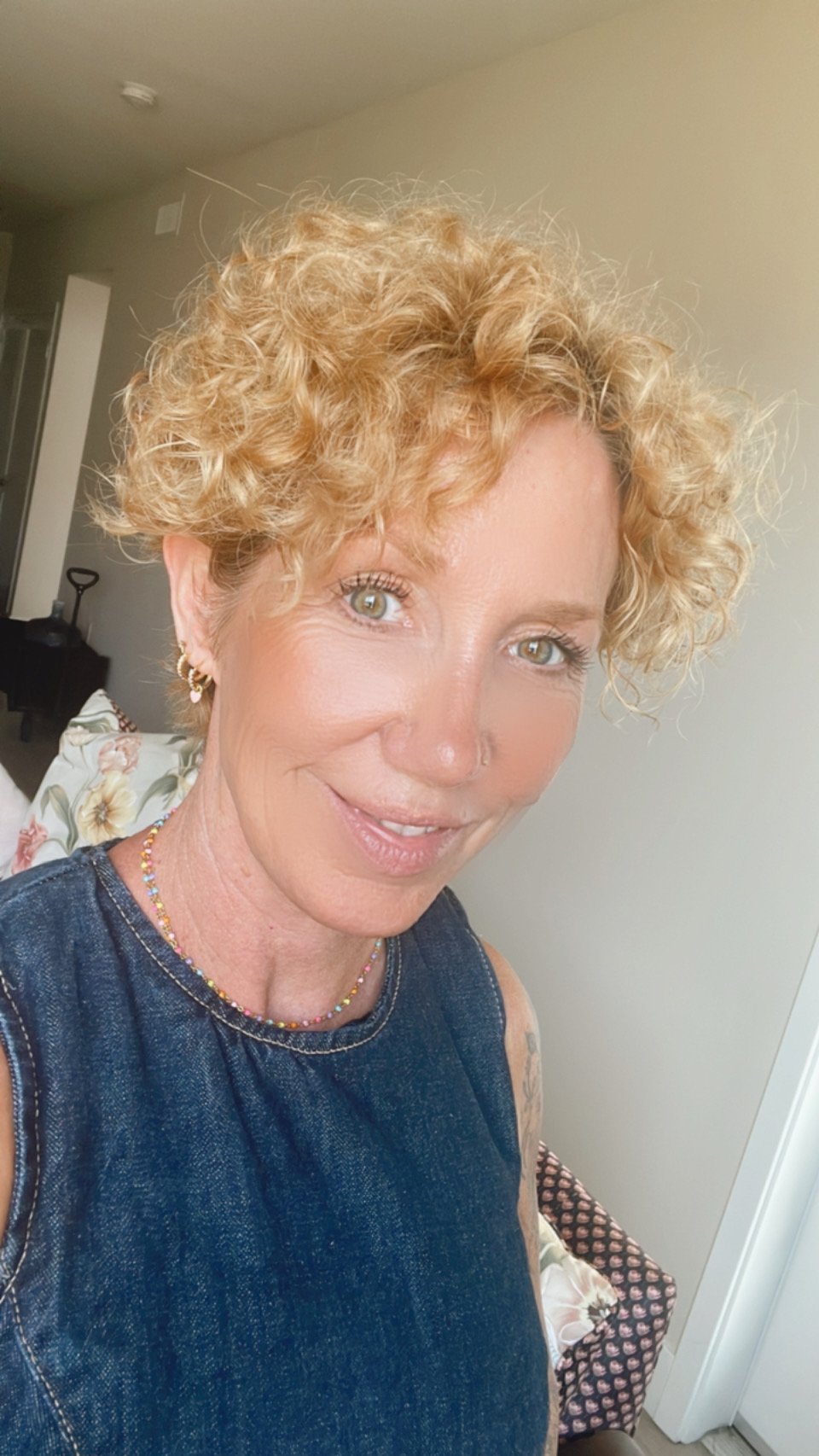 sabine schoepke with red curly hair and a jeans dress smiling at the camera