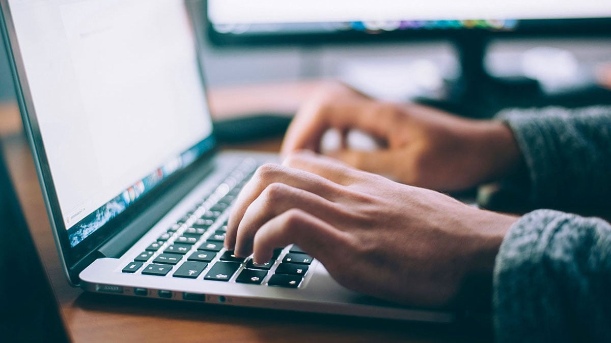 Person typing on a laptop with documents open on screen, symbolizing The Creative Guide blogs with reflections on creativity, communication, and photography practice.