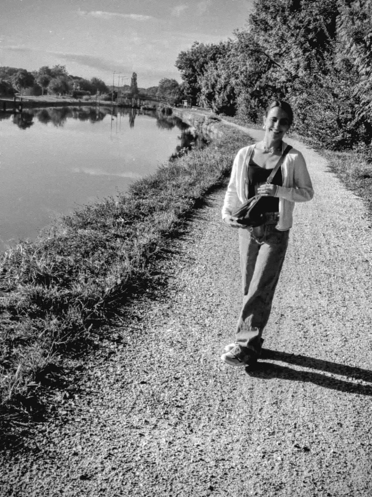 photo en noir et blanc de Manon marchant au bord d'un canal, symbole de résilience, bien-être et reconnexion à soi - entrecorpsetracine