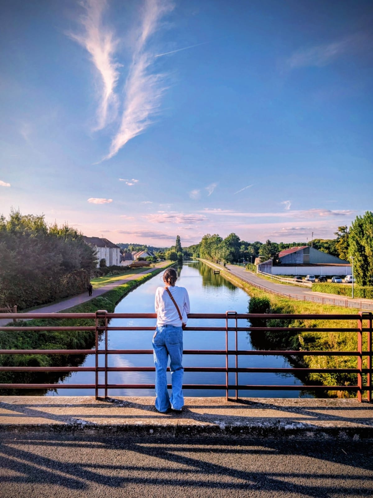 photo personelle de Manon Bouillot, créatrice de entrecorpsetracine, marchant sur un pont au coucher de soleil, symbole de cheminement et de bien-être