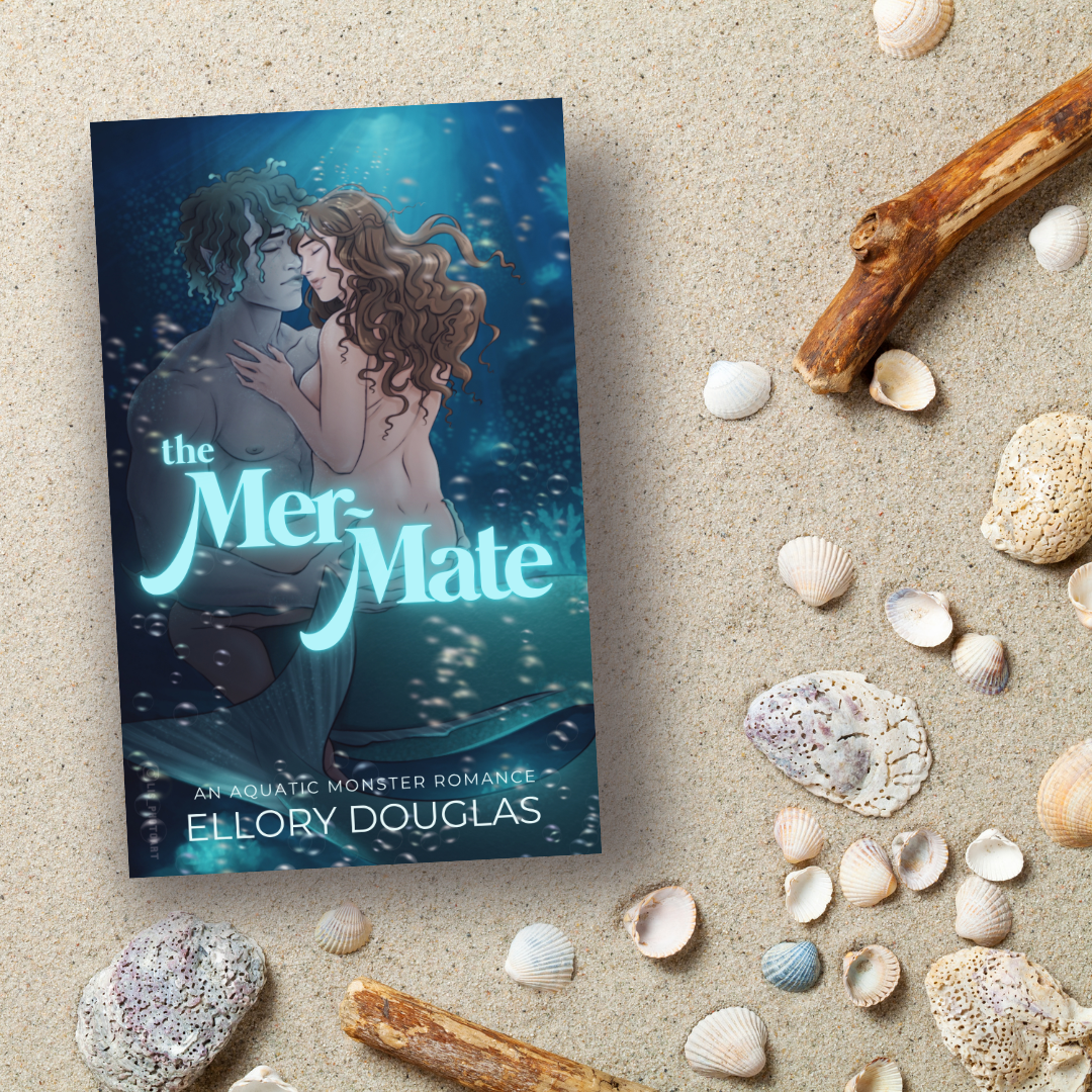 A flat lay of The Mer-Mate book on a backdrop of sand, shells, and driftwood