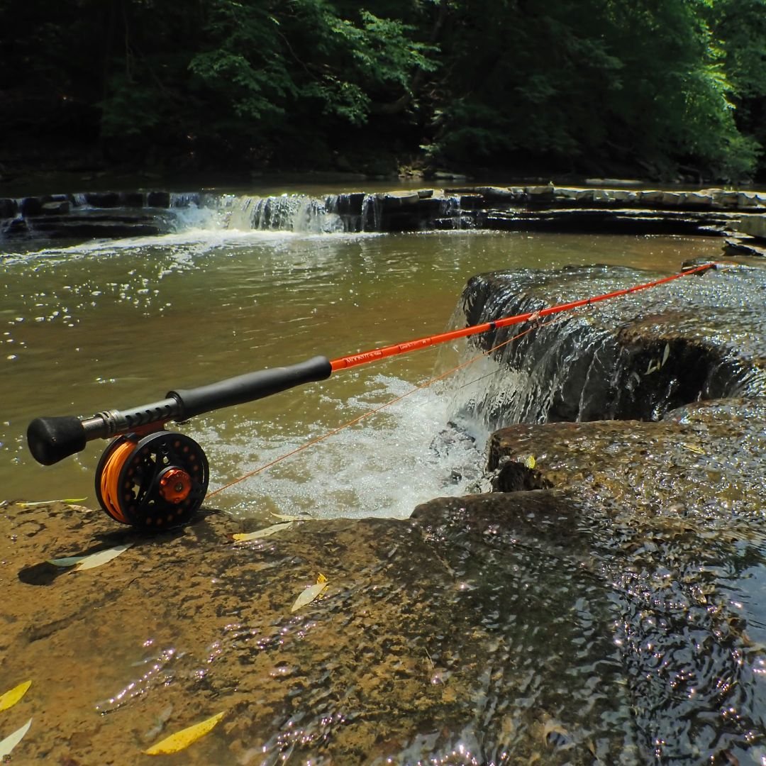 Fiberglass fly rod and reel resting across a small waterfall on the Chagrin River in Ohio.