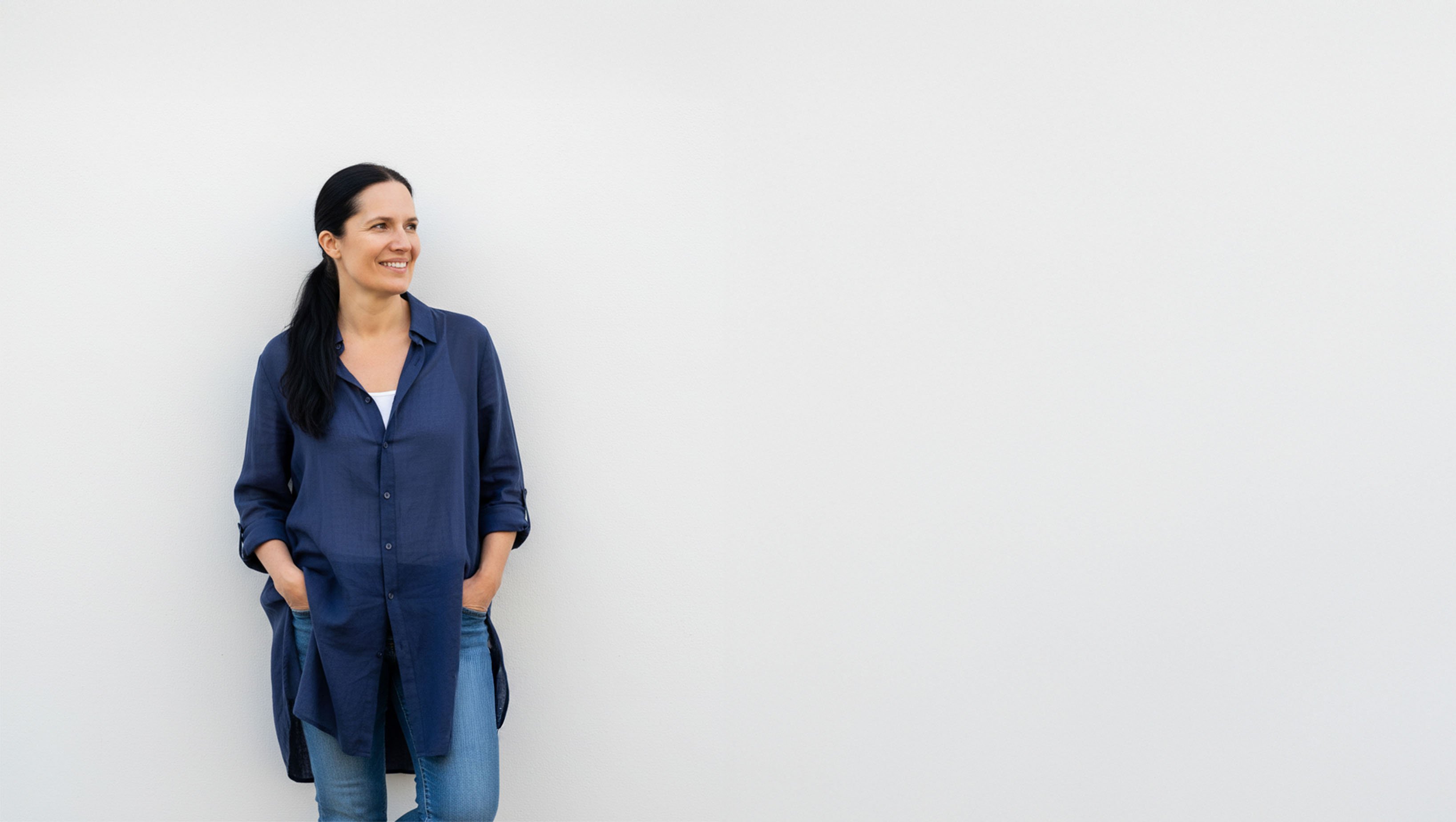 Mette standing smiling against a white wall