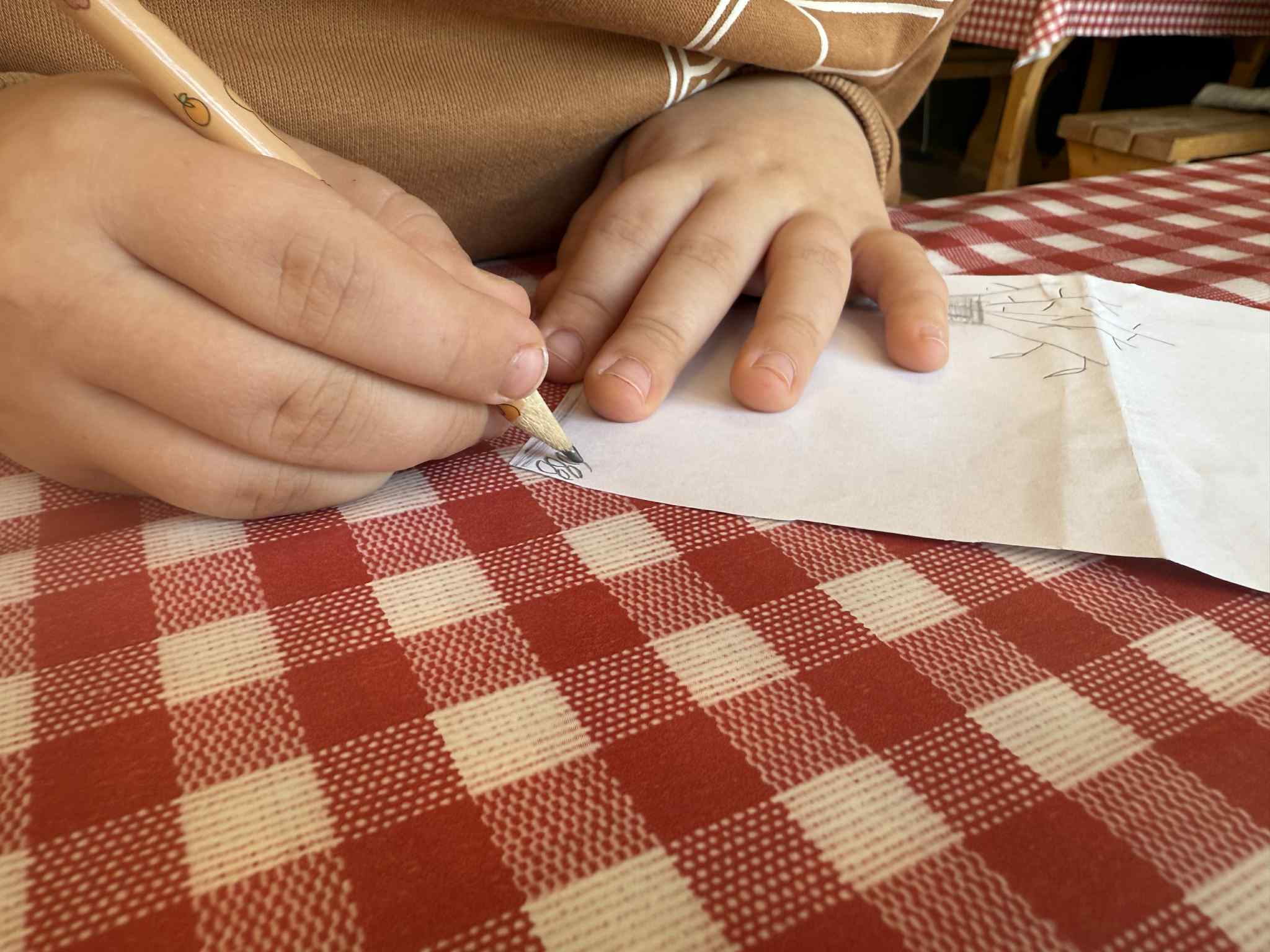 Child drawing on paper at checkered table - Payhip