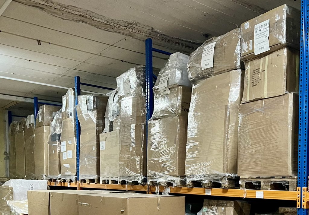 Sortierte Restposten Großhandel: Übersichtliche Lagerhaltung mit Paletten, die nach Warengruppen wie Heimtextilien, Küchenutensilien und Werkzeug geordnet sind. Ideale Großhandelspreise für gezielten Einkauf