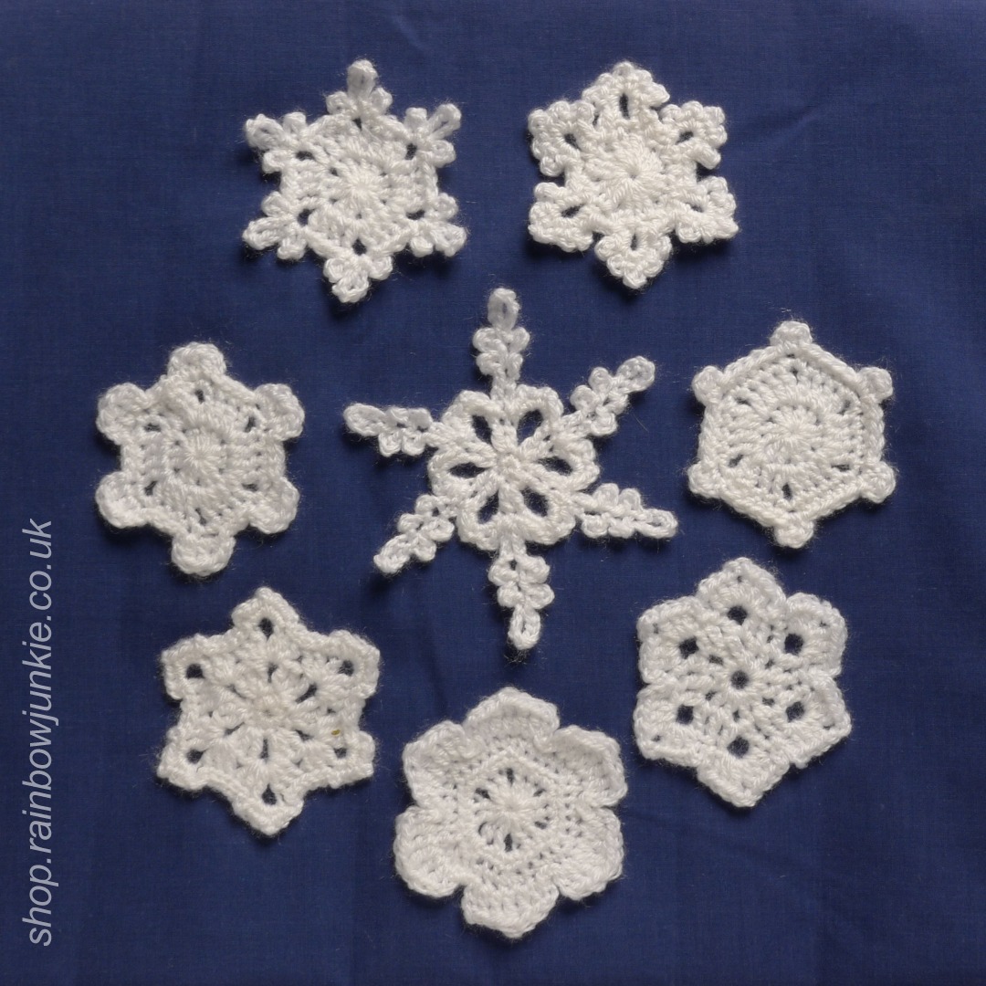 All eight snowflakes made in white DK acrylic on a dark blue background.