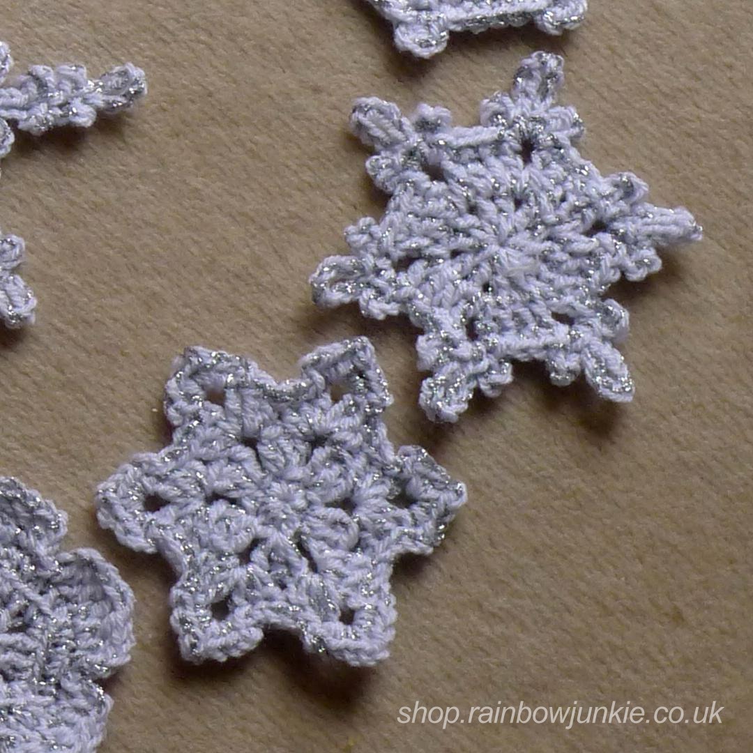 Two snowflakes made in mixed silver and white DK acrylic.