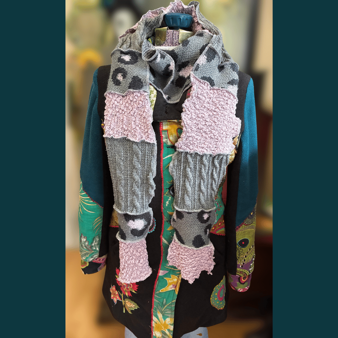 Upcycled scrappy scarf in soft pink and grey tones with wavy serged edges, handmade from rescued sweater fabric by What in Narnation.