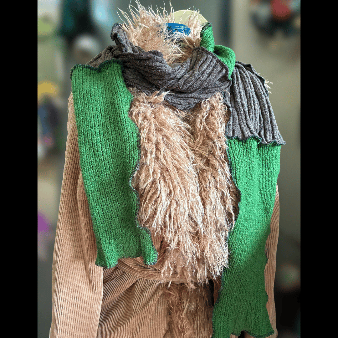 Upcycled scrappy scarf in earthy greens and warm browns, made from rescued sweaters with wavy serged edges, handcrafted by What in Narnation.