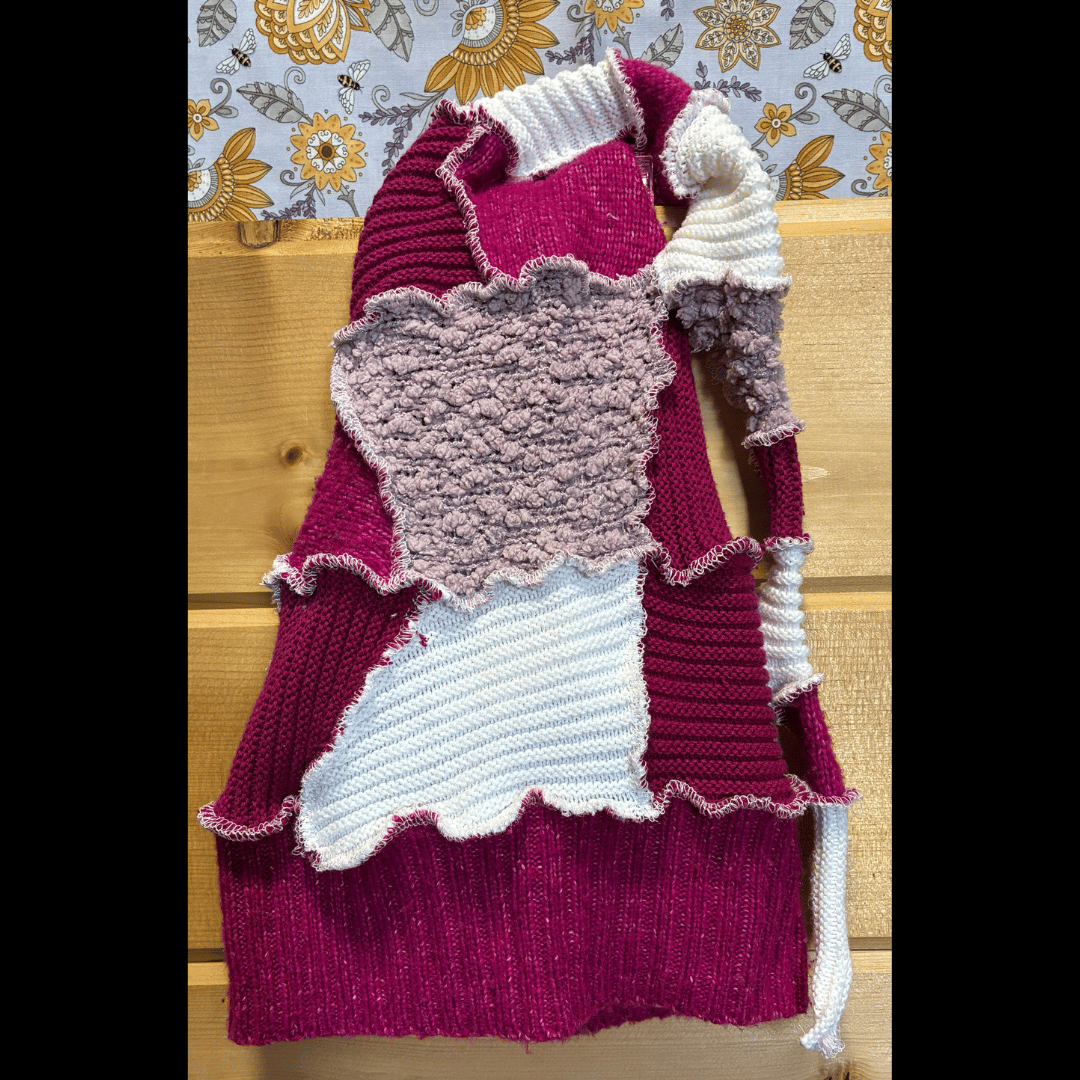 Handmade upcycled scrappy pixie hat in deep raspberry and bright white tones, crafted from rescued sweaters with playful wavy edges by What in Narnation.