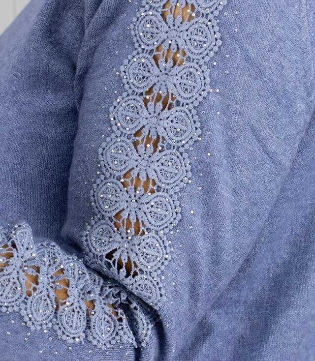 Detailansicht eines Pullover mit Spitzenbesatz und Strasssteinen an der Ärmelnaht.