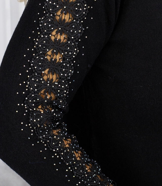 Detailansicht des schwarzen Pullovers mit eleganter Spitze und Glitzersteinen an den Ärmel.