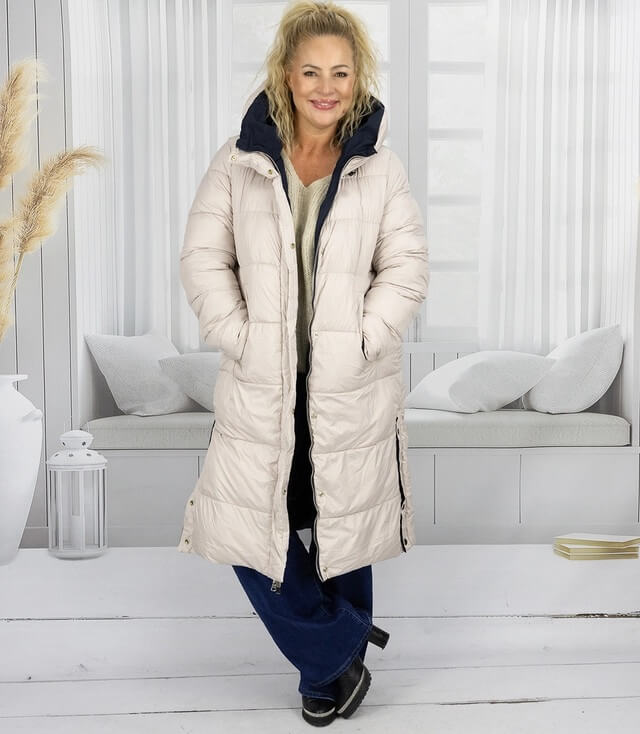 Beige Daunenjacke mit Kapuze, schmal geschnitten, bequem getragen von einer Frau in modischer Pose.