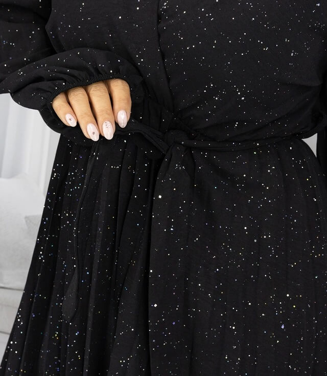 Detailansicht eines schwarzen Kleides mit Glitzer und Bindegürtel, das elegant und modisch aussieht.
