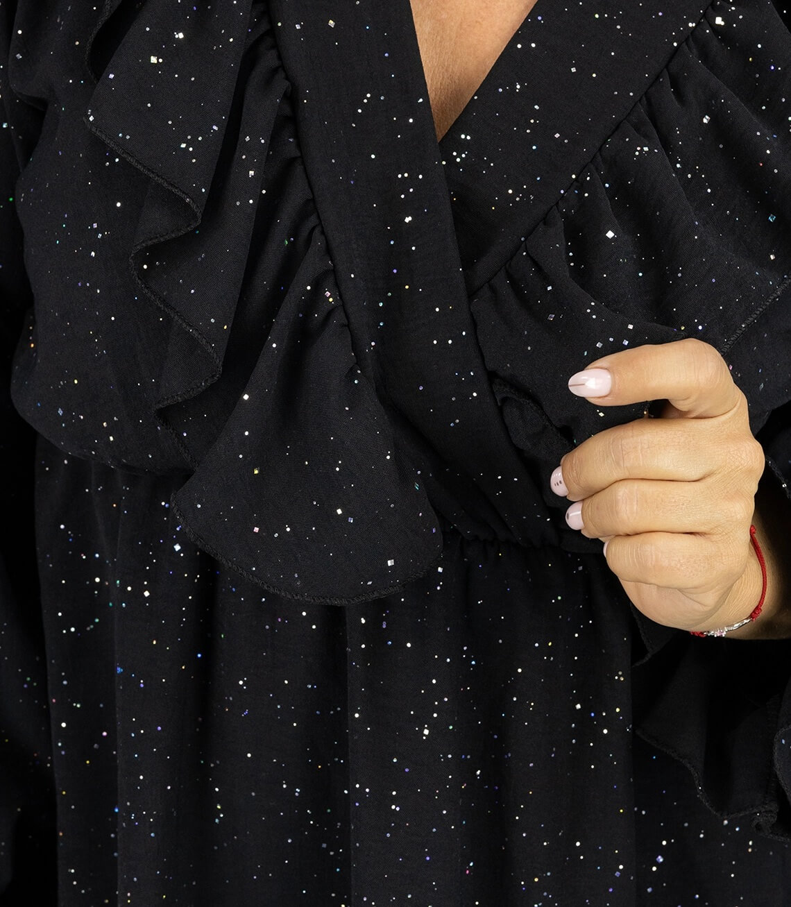 Detailbild eines schwarzen Kleides mit Rüschen und funkelnden Glitzerpunkten.