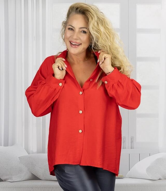 Frau in roter Bluse mit Knöpfen und lässigem Kragen, lächelt in hellem Raum.