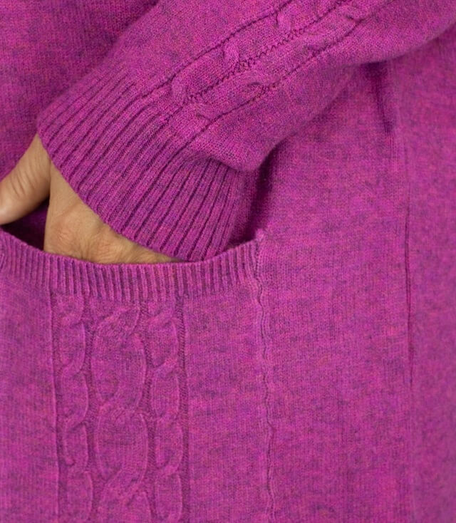 Detailansicht des strickkleids in Rosa mit Zopfmuster und warmem, weichem Material.