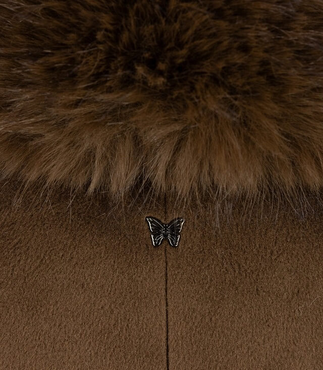 Detailansicht des Kragens mit weichem Pelz und Schmetterlings-Anhänger auf einem braunen Mantel.