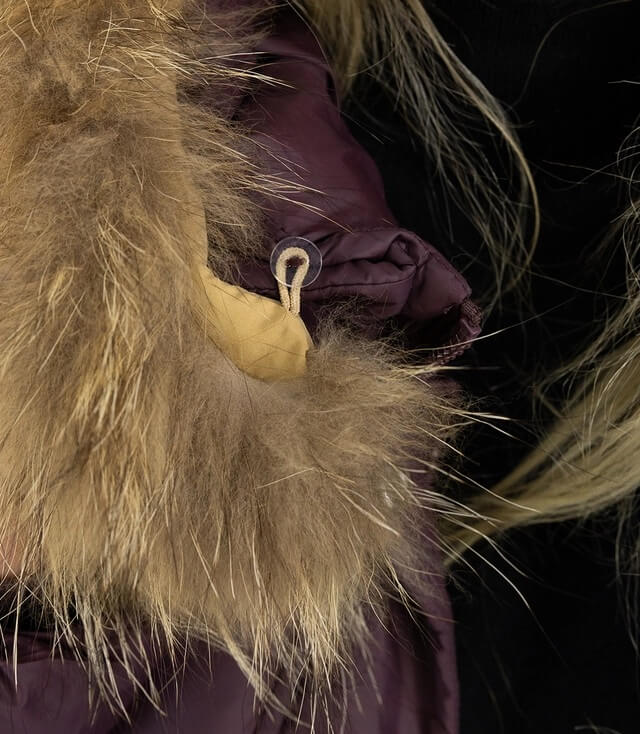 Detailansicht des Bauschals aus Kunstfell an einer lila Winterjacke.