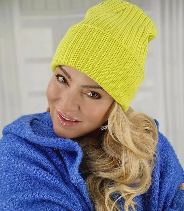Frau trägt eine leuchtend gelbe Strickmütze, ergänzt mit einem blauen, gemütlichen Pullover.