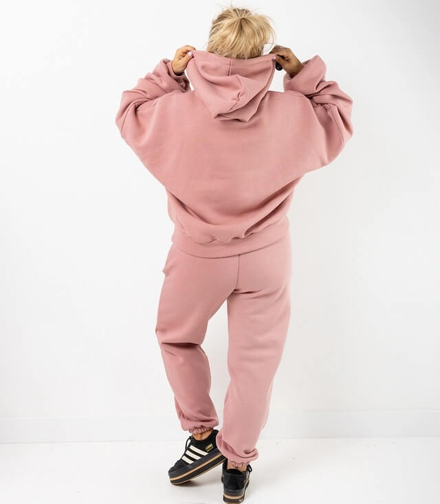 Rückansicht einer Person in rosa Kapuzenpullover und Jogginghose, bequem und stylish.