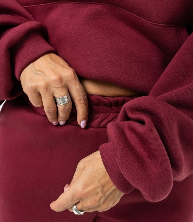 Detailansicht vom burgunderfarbenen Jogginganzug mit elastischem Bund und lässigem Design.