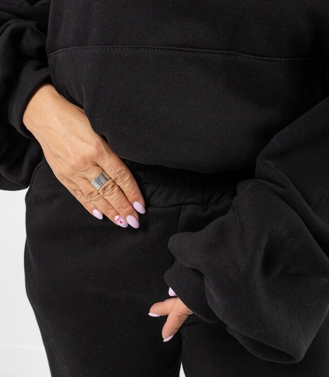 Detailansicht des schwarzen Sweatshirts mit weiten Ärmeln und elastischem Bund.