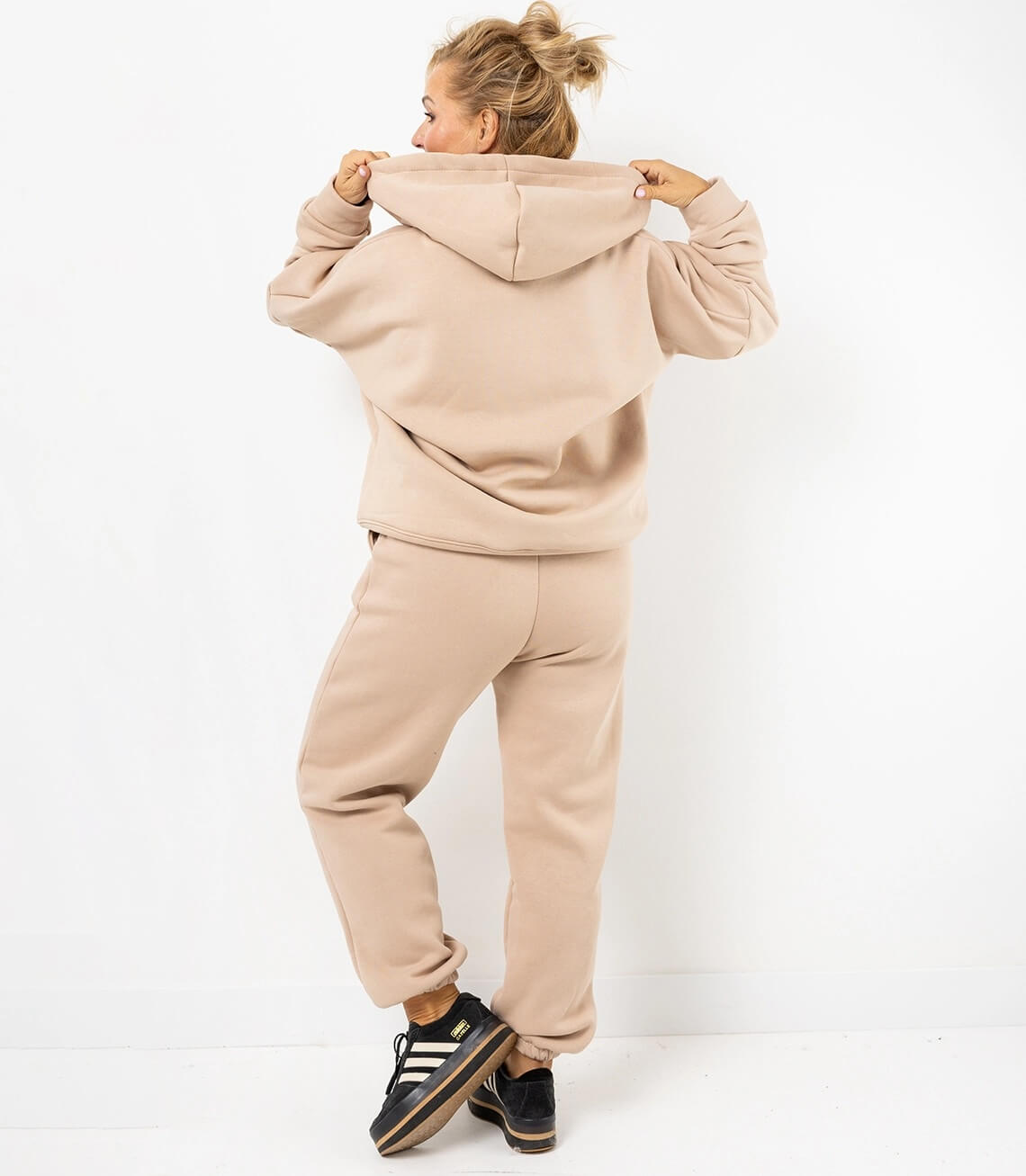 Damen Sweatanzug in Beige mit Kapuze, Rückenansicht, lässig und bequem, kombiniert mit Sneakern.
