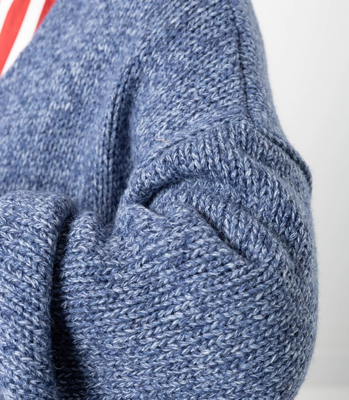 Detailansicht von dem blauen Strickmantel mit sichtbaren Texturen und einem weichen Material.