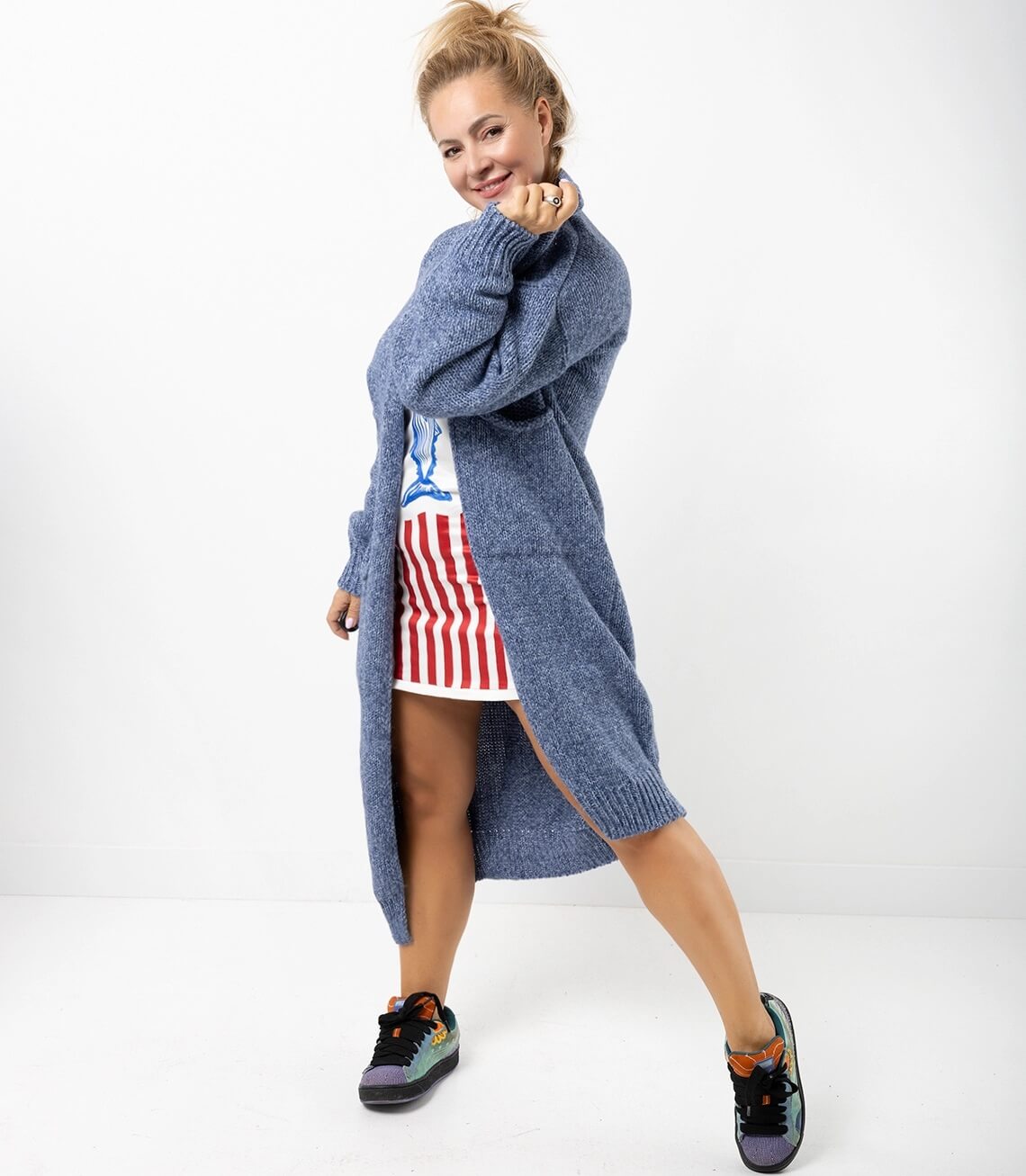 Stylischer blauer langer Strickmantel, offenes Design, kombiniert mit Sneaker für einen lässigen Look.