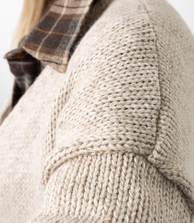 Detailansicht des Strickmantels mit strukturiertem Strick und Karottenhemdkragen.