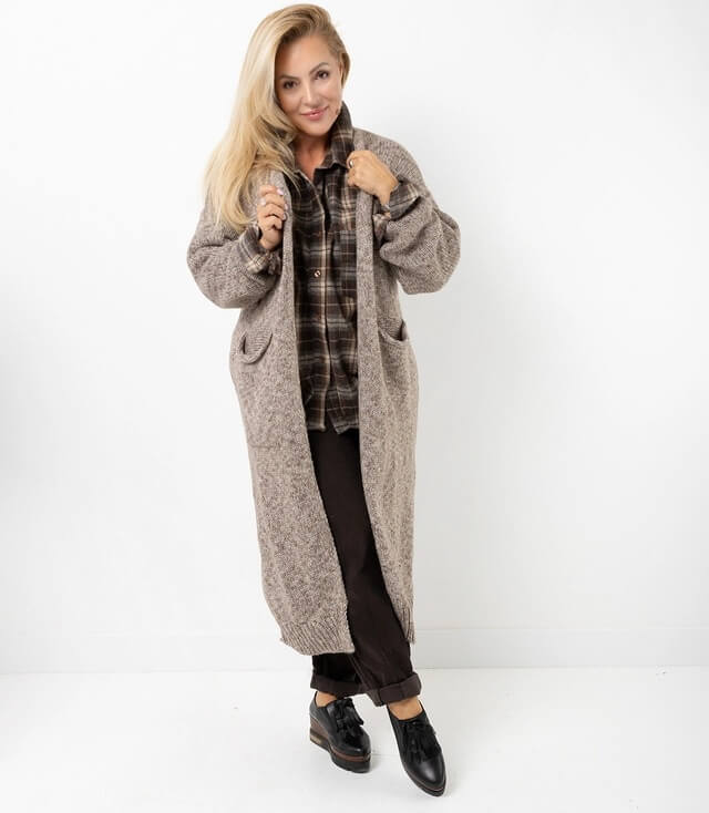 Frau trägt einen langen, braunen Strick Cardigan mit Taschen und lässiger Karobluse, perfekt für einen gemütlichen Look.