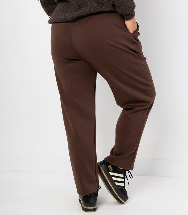 Rückansicht einer braunen Hose mit lockerer Passform und seitlichen Taschen, kombiniert mit sportlichen Schuhen.