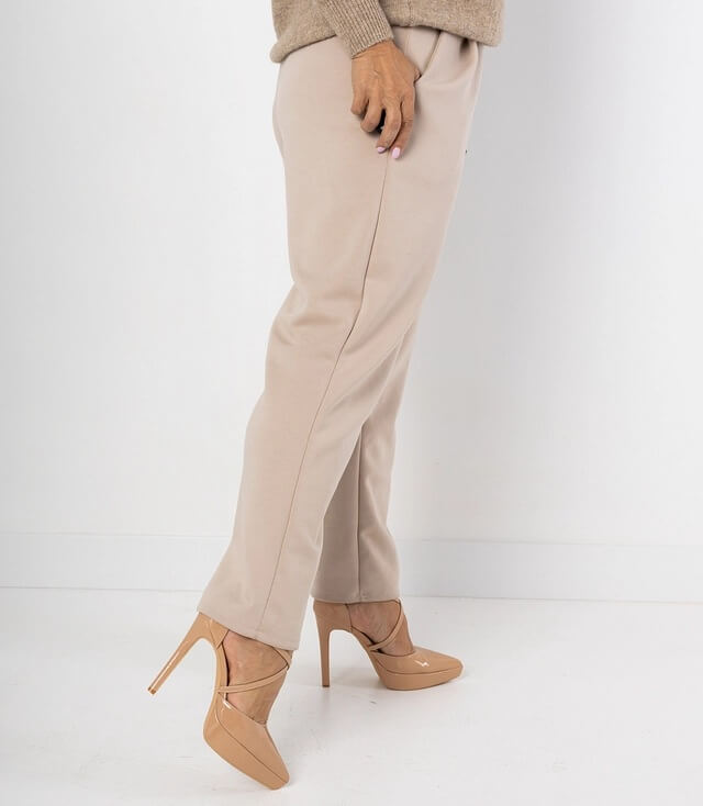 Seitenansicht einer beigen Hose, kombiniert mit stylischen High Heels in Nude-Farbe.