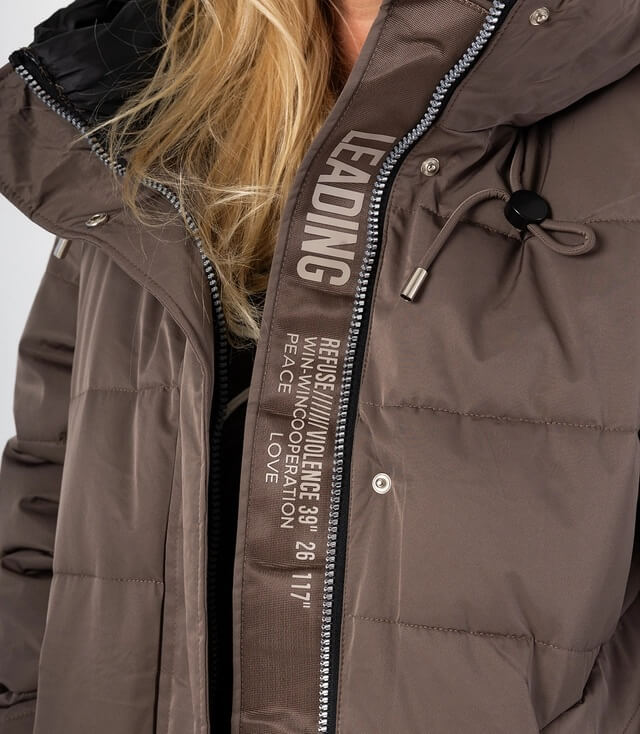 Detaillierte Ansicht einer warmen Jacke mit Reißverschluss und Schriftzügen auf der Vorderseite.