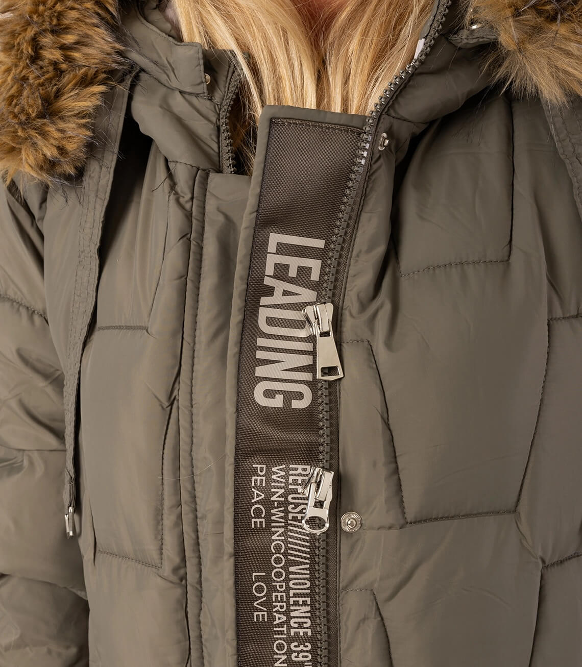 Detailansicht einer grauen Winterjacke mit Kapuze und einem auffälligen Reißverschluss mit Schriftzügen.