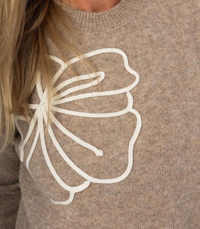 Brauner Pullover mit eleganter weißer Blumenausschnitt-Stickerei auf der Vorderseite.
