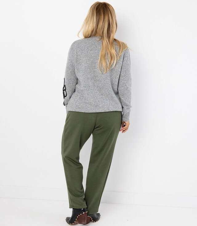 Rückenansicht einer grauen Strickjacke mit grüner Hose, im lässigen Look.