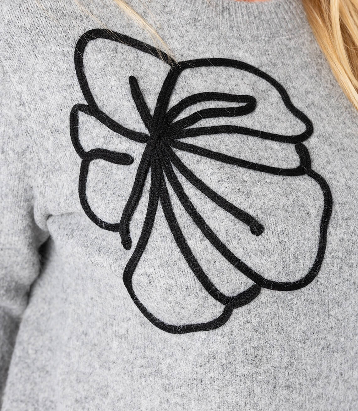 Grauer Pullover mit schwarzem Blumen-Design auf der Vorderseite, ideal für lässige Looks.