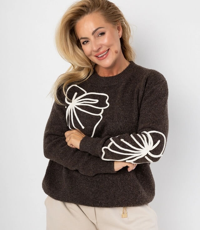 Dunkelbrauner Pullover mit weißen Schleifenmotiven an den Ärmeln, schick und bequem für jeden Anlass.